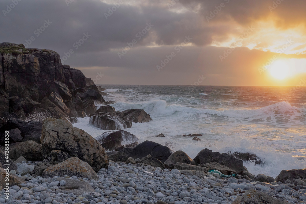 Rugged stone coast line and ocean waves at sunset. West of Ireland. Irish landscape. Dramatic sky. Sun flare. Irish landscape. Nature power and beauty concept