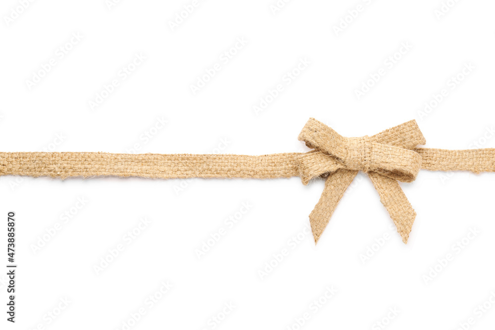 Fototapeta premium Burlap ribbon with pretty bow on white background, top view