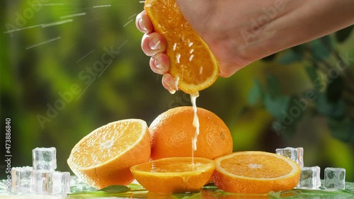 Hand squeezing orange on nature background. Organic citrus juice close-up. Spa treatments. Skincare, cosmetics and beauty concept.