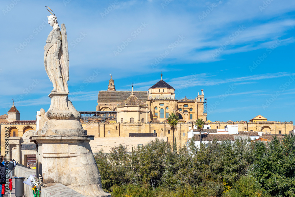 The statue of Archangel Raphael on the ancient Roman Bridge with the Mezquita Mosque Cathedral and town of Cordoba Spain in view.	