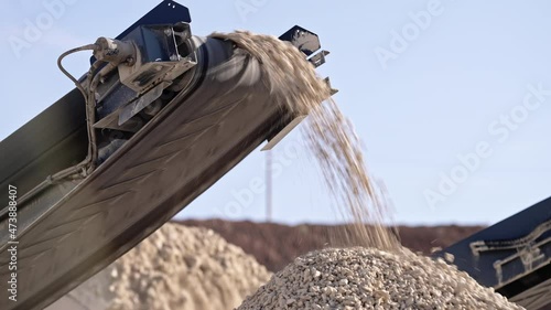Mobile portable crushing screening plant. Mining conveyor belt sorts rock and loading stones in truck. Heavy machinery working for minerals extraction. Mining extractive industry.