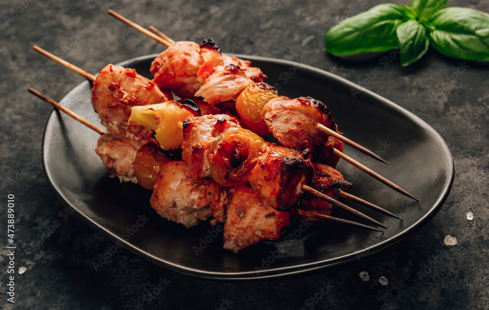 Grilled chicken on bamboo skewers with basil on black background. Selective focus Grilled chicken on bamboo skewers with basil on black background. Selective focus