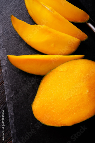 Ripe egyption Mango slices served  at black dish. close up