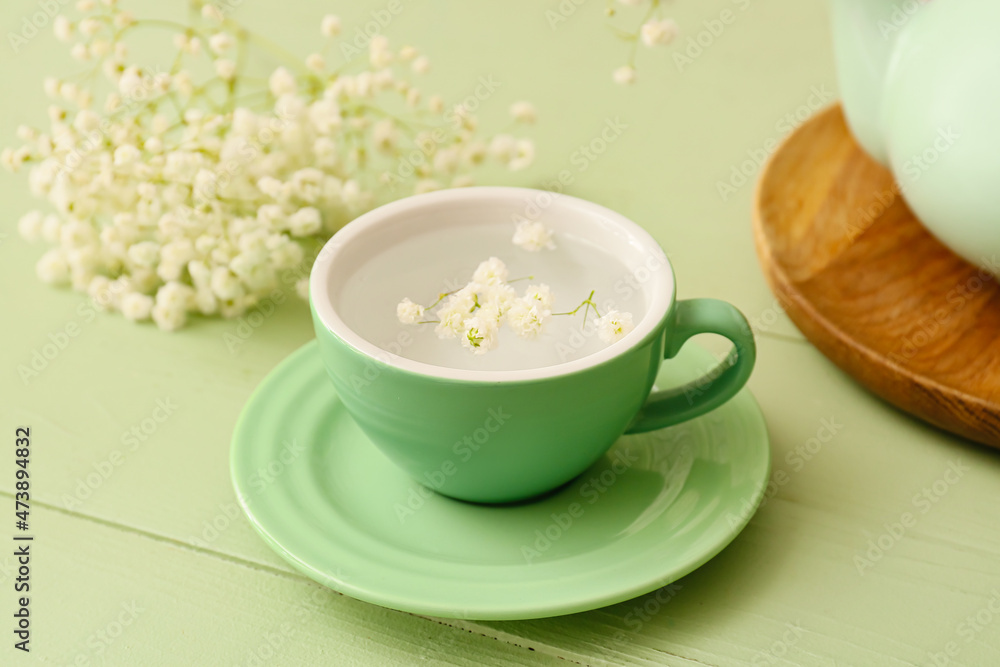 Cup of water with beautiful gypsophila flowers on wooden table, closeup Cup of water with beautiful gypsophila flowers on wooden table, closeup