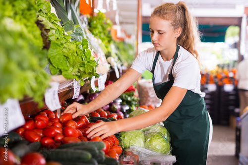 Fotografie Focused fifteen-year-old girl who works part-time in a store as a trainee salesw