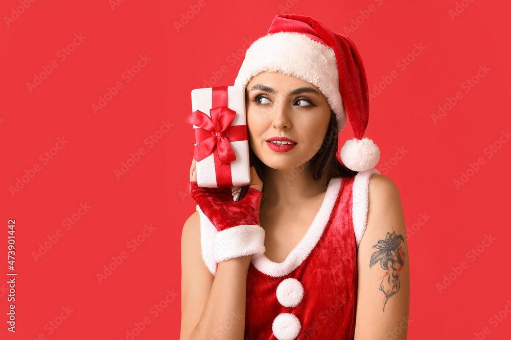 Sexy young woman in Santa costume and with Christmas gift on color background Sexy young woman in Santa costume and with Christmas gift on color background