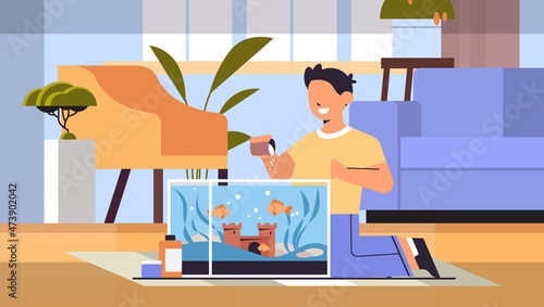 boy feeding fishes in aquarium domestic animal friendship with pet concept living room interior