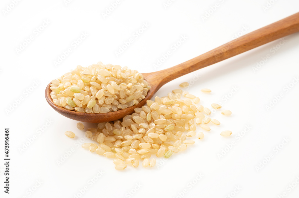 Brown rice in a wooden spoon placed on a white background. Brown rice in a wooden spoon placed on a white background.