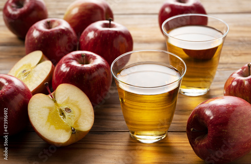 Apple juice in a glass cup against a wooden background.