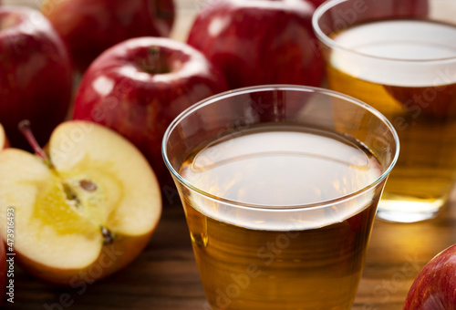 Apple juice in a glass cup against a wooden background.