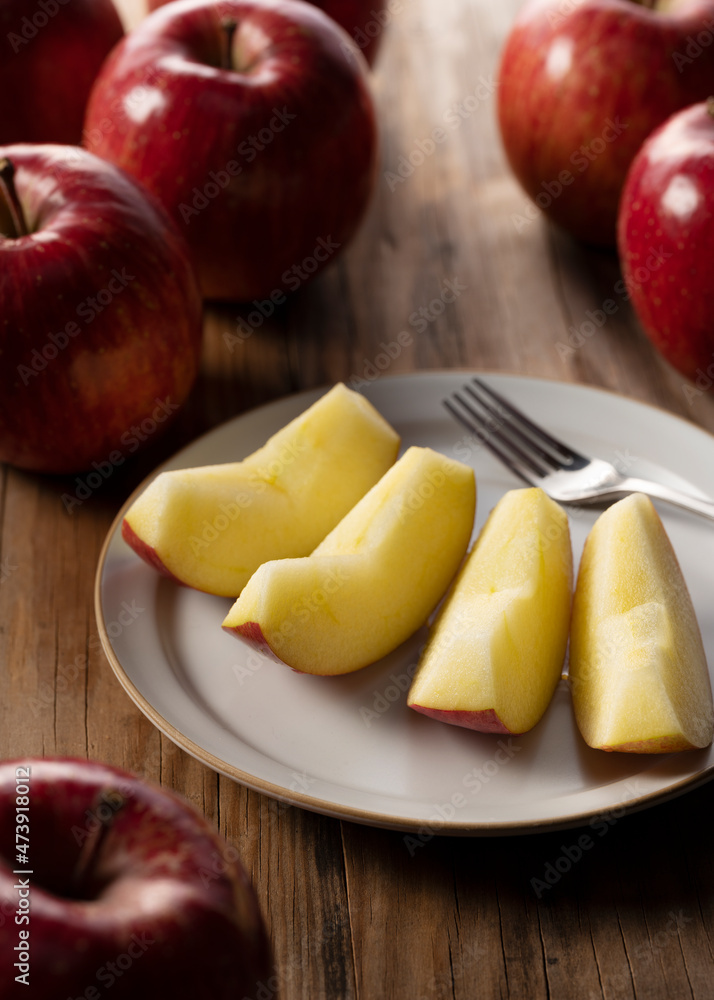 Cut apples on a plate against a wooden background.