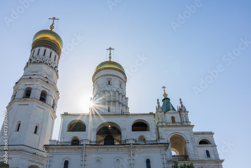 Ivan the Great Bell Tower, with Assumption Belfry on the right in Moscow Kremlin. Blue sky background with sunbeams