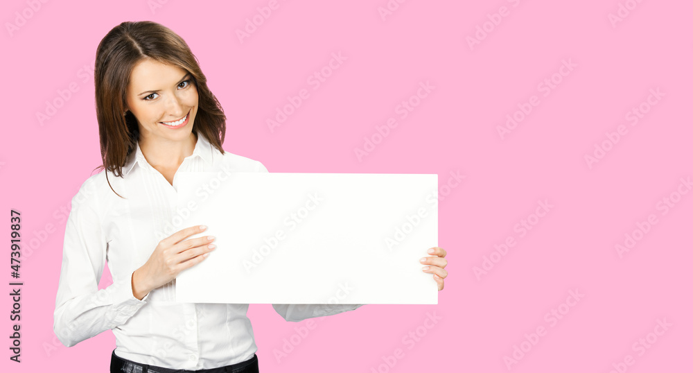 Happy smiling woman in white confident wear holding showing mock up empty signboard. Businesswoman in advertising studio concept. Copy space area. Rose pink color background.. Happy smiling woman in white confident wear holding showing mock up empty signboard. Businesswoman in advertising studio concept. Copy space area. Rose pink color background..