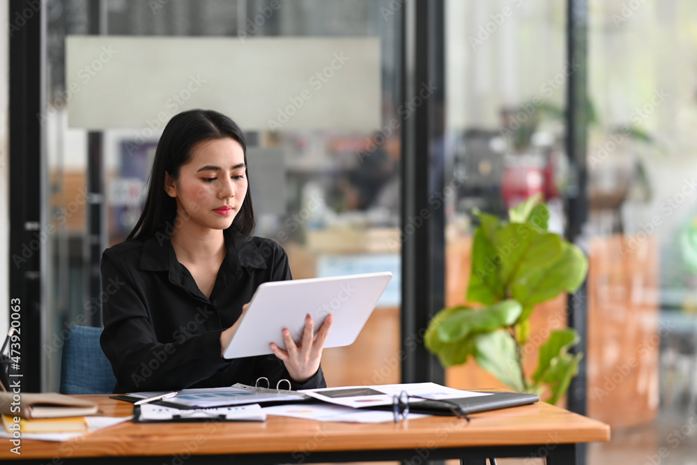Young businesswoman using digital tablet while sitting modern workplace. Young businesswoman using digital tablet while sitting modern workplace.