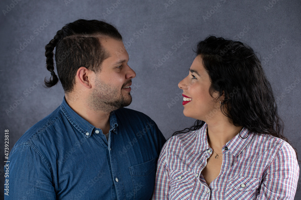 Young couple in a studio portrait while they look at each other in love Young couple in a studio portrait while they look at each other in love