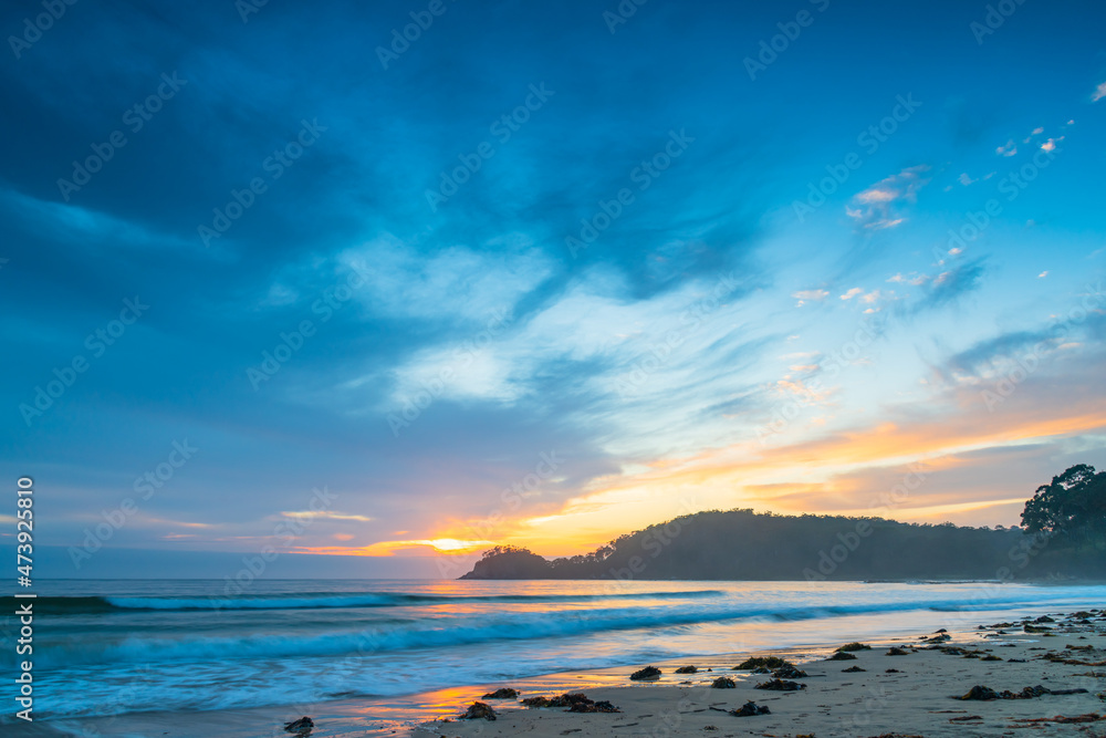 Fototapeta premium Sunrise at the seaside with cloud cover and seaweed