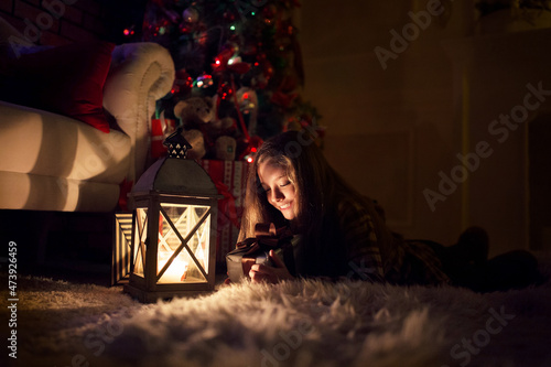 A girl near a Christmas tree with a decorative lantern in her hands  New Year and Christmas.