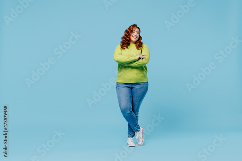 Foto Full body confident happy young chubby overweight plus size big fat fit woman wear green sweater hold hands crossed folded isolated on plain blue background studio portrait