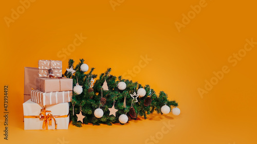 Decorated Christmas tree fallen down. Christmas gifts near fallen tree. Scandinavian Christmas tree.