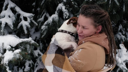 playful woman with dog. stylish hipster woman hugging and smiling cute jack russell terrier in snowy cold winter park. moments of true happiness. photo