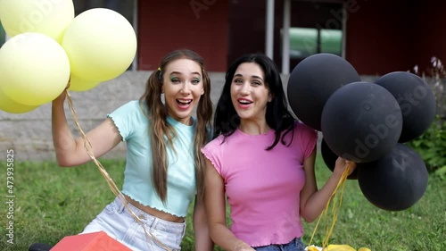 Two young girls are playing with balloons in the park. photo