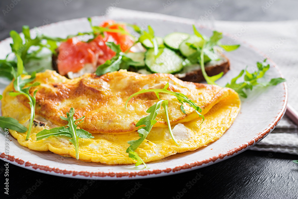 Breakfast. Omelette with cheese and sandwiches with salmon and cucumber on white plate. Frittata - italian omelet. Breakfast. Omelette with cheese and sandwiches with salmon and cucumber on white plate. Frittata - italian omelet.