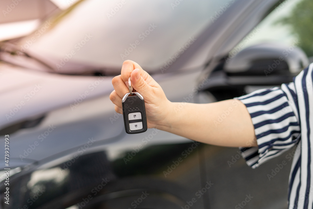 Obraz premium An employee of a tourist car rental company presents the car keys with a test drive. Good service before agreeing to a lease or purchase contract.