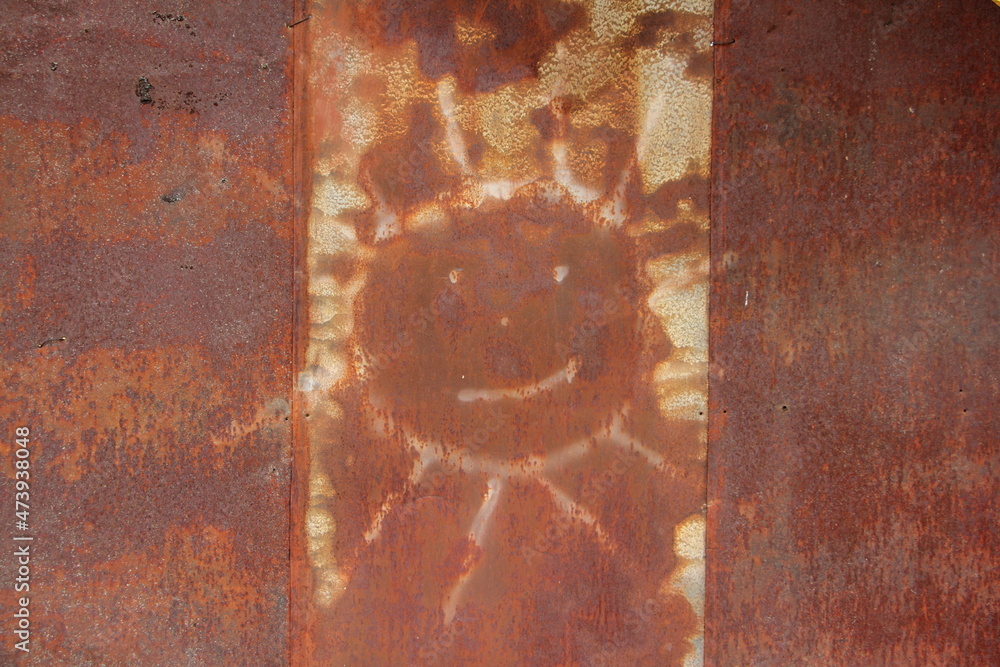 An old drawing of the sun on a rusty iron wall concept background texture