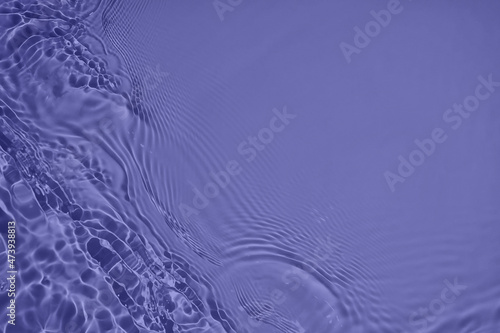 Transparent purple water surface texture with ripples, splashes and bubbles. Abstract nature background Water waves in sunlight with copy space Cosmetic moisturizer micellar toner emulsion. 2022 color
