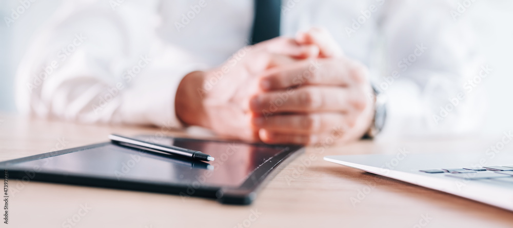 E-signature stylus and pad on business office desk, hands of a businessman in background, panoramic image E-signature stylus and pad on business office desk, hands of a businessman in background, panoramic image