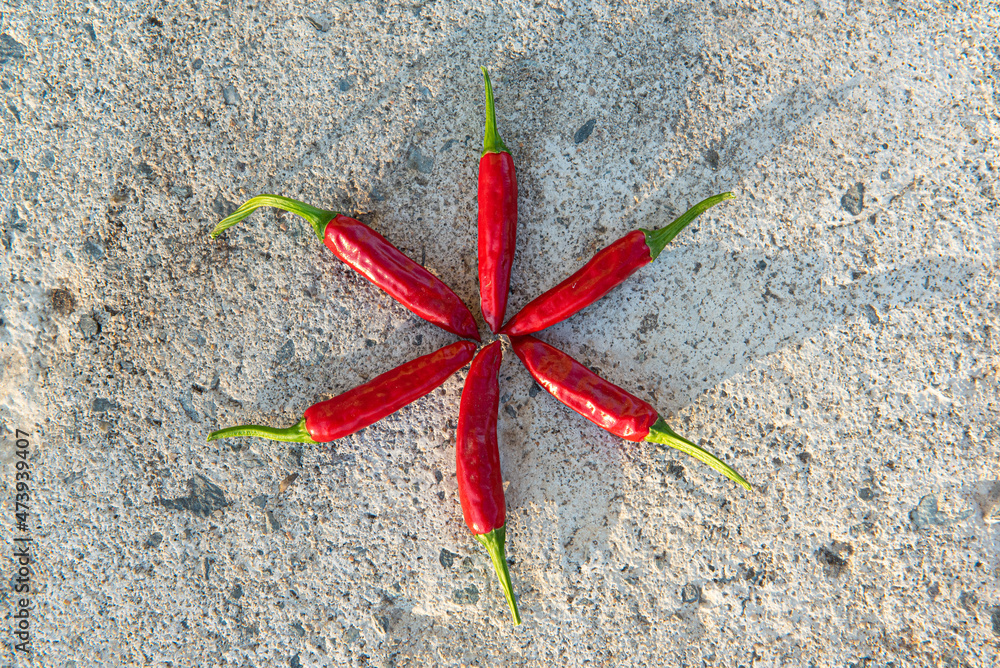 Many small hot red chili peppers close-up, lying on a stone background. Rustic background. Top view, flat lay Many small hot red chili peppers close-up, lying on a stone background. Rustic background. Top view, flat lay