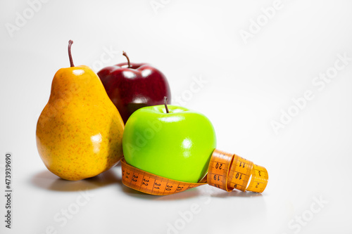 Healthy and healthy snack: green apple, ripe pear and red apple and measuring tape, diet and sports on a white background with space for text. The concept of a healthy lifestyle, the benefits of fruit