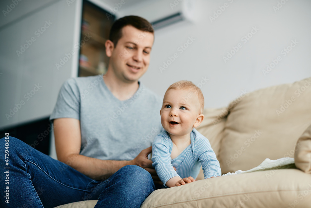 Happy baby boy crawls on sofa while spending time with his father at home. Happy baby boy crawls on sofa while spending time with his father at home.
