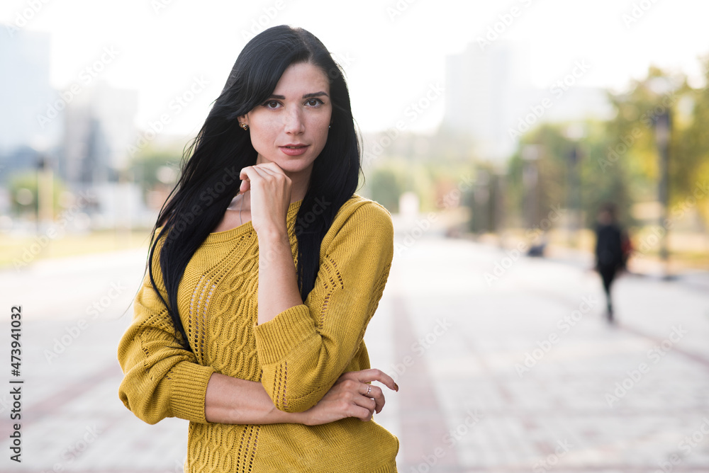 Beautiful and attractive Caucasian brunette girl in a yellow sweater posing while walking. Beautiful and attractive Caucasian brunette girl in a yellow sweater posing while walking.