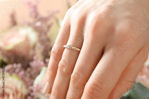 Female hand with wedding ring on wedding bouquet background