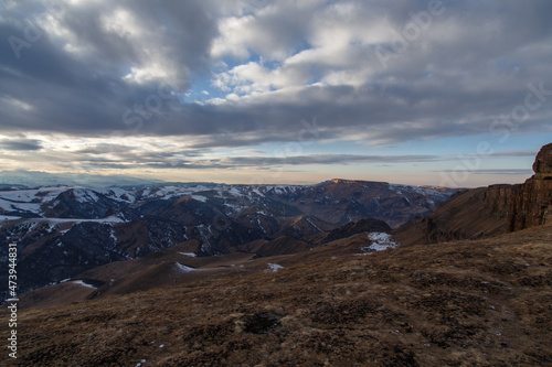 The setting sun illuminates the mountain range through the clouds