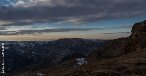 The setting sun illuminates the mountain range through the clouds