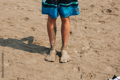 Closeup of the man's muddy feet on the beach.