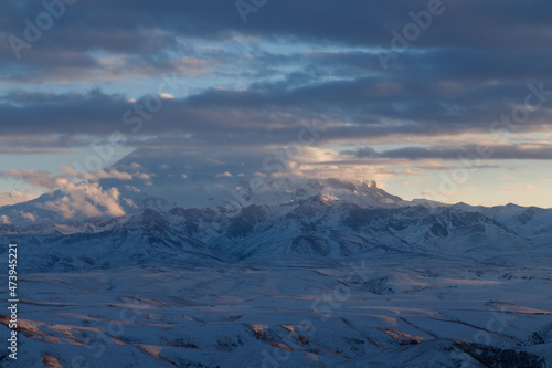 Elbrus in the clouds in the light of the sunset rays © Aleksandr