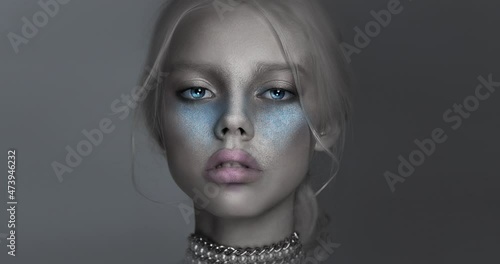 Portrait of a girl. Mystical silver face. The eyes close. photo