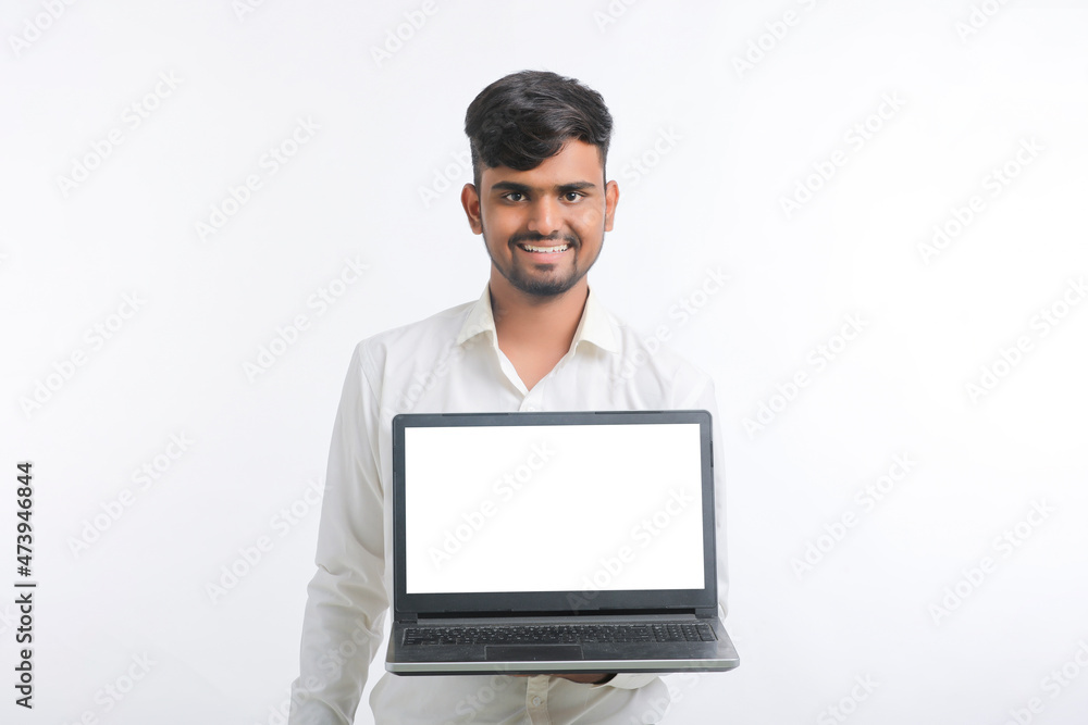 Young indian man showing laptop screen with copy space on white background. Young indian man showing laptop screen with copy space on white background.