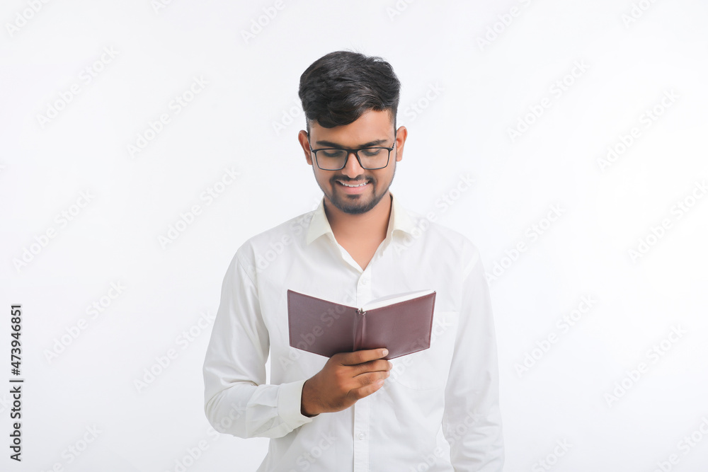 Young Indian man standing and holding dairy in hand on white background. Young Indian man standing and holding dairy in hand on white background.