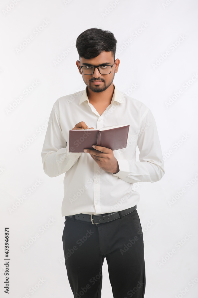 Young Indian male writing some detail in dairy over white background.