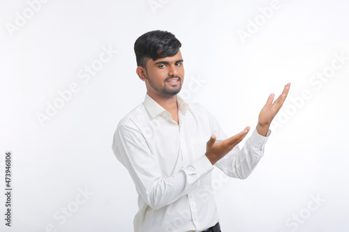 Young indian man giving expression with hand over white background.