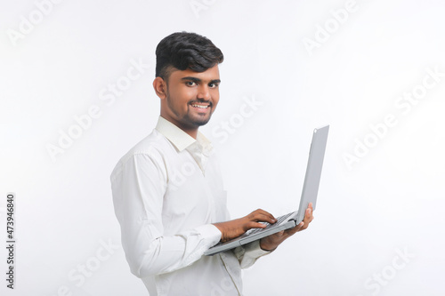 Young indian man using laptop over white background.