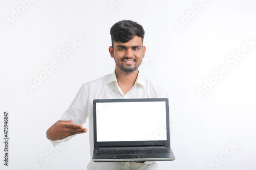 Young indian man showing laptop screen with copy space on white background. © PRASANNAPIX