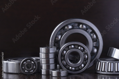 A set of steel bearings on a dark background. Ball radial and tapered plain bearings for mechanical engineering, heavy equipment and machine tools close-up. Round bearings in different sizes.
