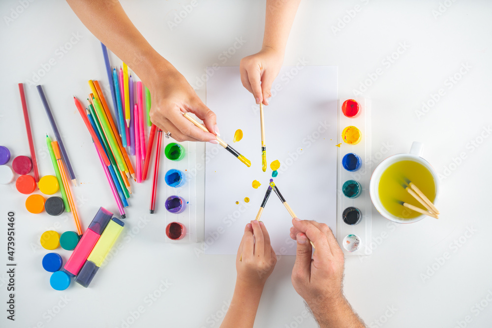 Humans hand of mother father and children is drawing with colorful pencils. Top view to white table with art supplies. Artist painting, drawing art. Humans hand of mother father and children is drawing with colorful pencils. Top view to white table with art supplies. Artist painting, drawing art.