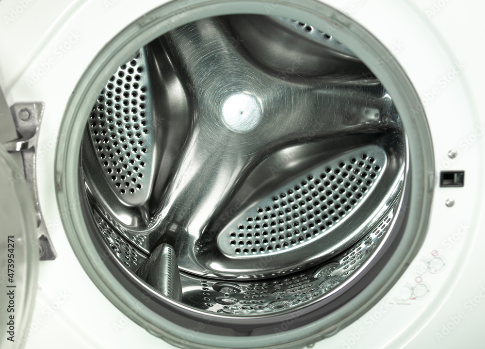 An empty stainless steel bubbled drum of white washing machine through opend door.