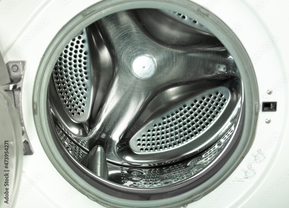 An empty stainless steel bubbled drum of white washing machine through opend door. An empty stainless steel bubbled drum of white washing machine through opend door.